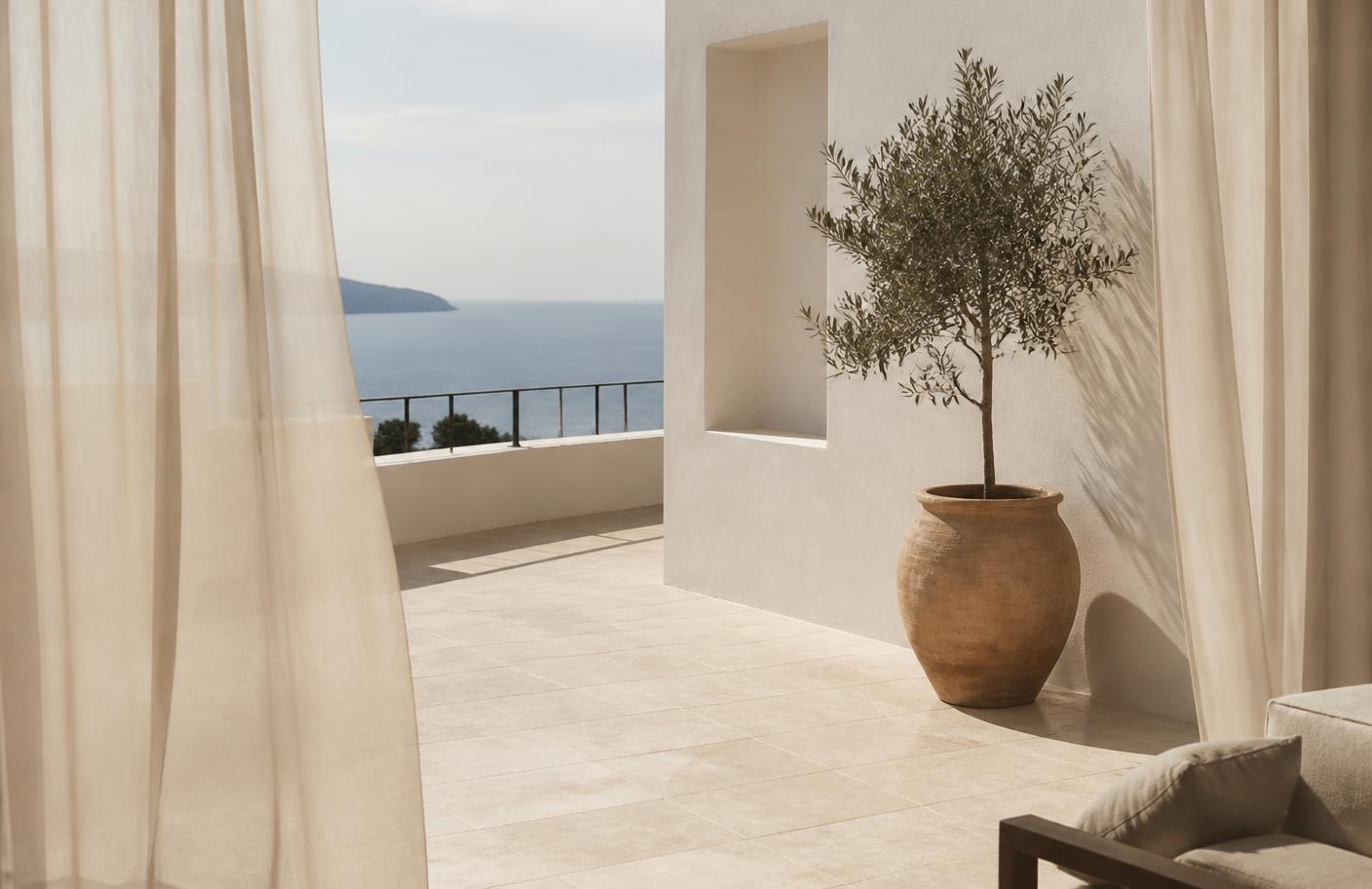 Quiet hotel terrace with olive tree and linen curtains